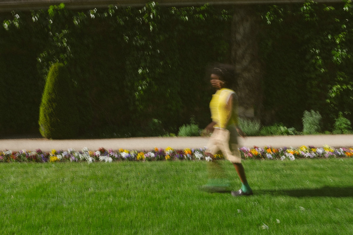 Person in a yellow top walking across a manicured lawn