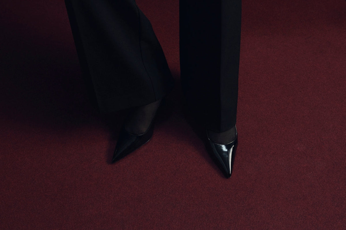 Black trousers and pointed shoes on deep red carpet