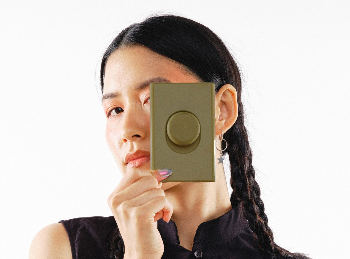 Model holding an olive Switch T-1 toggle in front of one eye