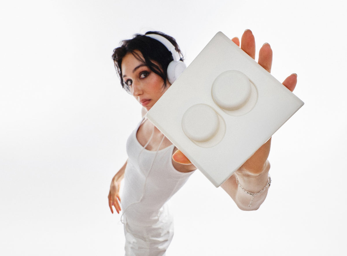 Model with short dark hair and white headphones holding a white Switch T-2 double toggle up to the camera